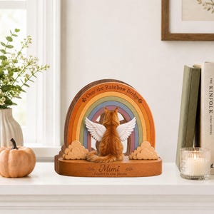 May include: A wooden memorial plaque featuring a ginger cat with white angel wings sitting before a colorful rainbow arch. The arch is inscribed with the text Over the Rainbow Bridge, and the base displays the name Mimi and Forever in Our Hearts.
