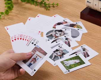 May include: A deck of custom playing cards featuring personalized photographs on the faces. The cards display various images, including a person standing in a doorway and dogs in outdoor settings, alongside standard suit symbols and card values.