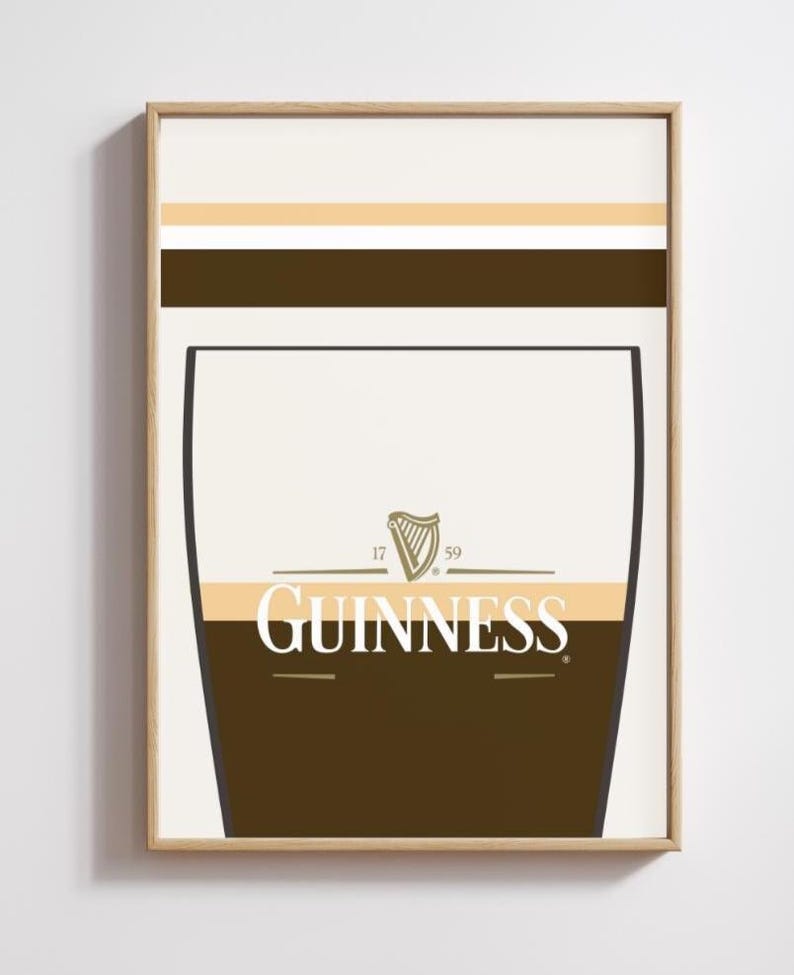 Op de afbeelding: Een ingelijste print met een gestileerd Guinness pintglasontwerp. Het kunstwerk heeft een bruin en beige kleurenschema met het Guinness-logo. De print heeft een lichtbeige achtergrond met bruine en gouden horizontale strepen. Pub-thema.