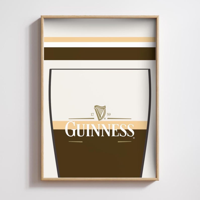 Op de afbeelding: Een ingelijste print met een gestileerd Guinness pintglas ontwerp. Het kunstwerk gebruikt wit, bruin en beige tinten, met het Guinness logo prominent weergegeven. De print zit in een lichtbruine houten lijst.