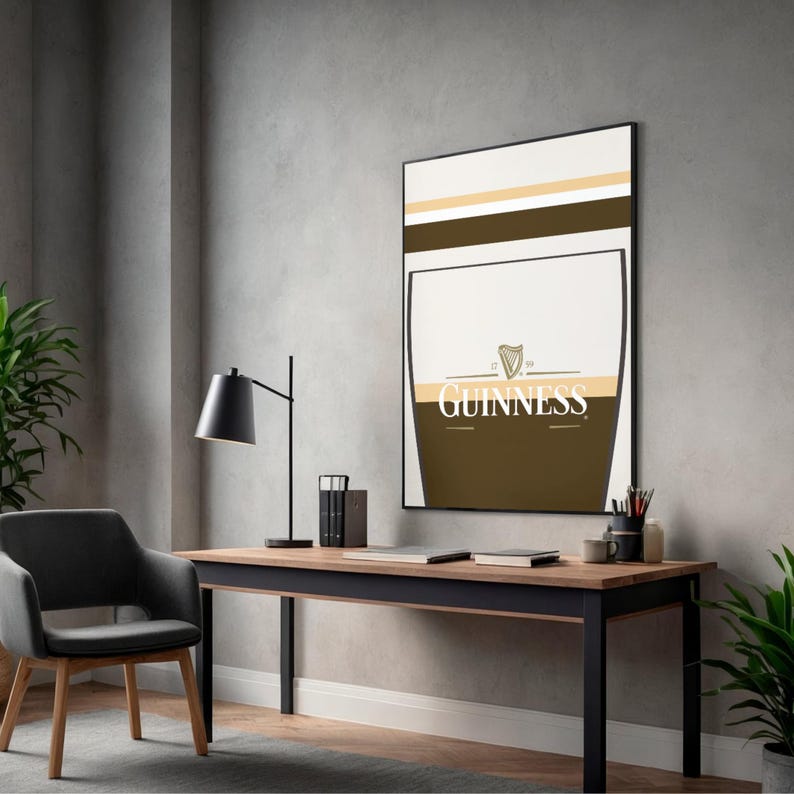 Op de afbeelding: Een ingelijste Guinness-poster met een gestileerd pintglasontwerp en het Guinness-logo. De poster hangt boven een houten bureau met een zwart frame, een zwarte bureaulamp en een zwarte stoel. De kamer heeft een moderne, minimalistische uitstraling. Het bureau is ongeveer 150 cm lang.