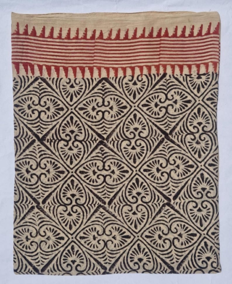 May include: A textile with a cream-colored background and a repeating pattern of dark brown floral shapes. The top border features a red striped design. The fabric is likely cotton or linen, suitable for home decor or apparel.