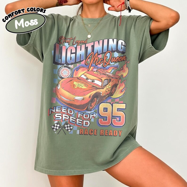 Puede incluir: Camiseta verde oliva con un dise&ntilde;o de Rayo McQueen de la pel&iacute;cula Cars. El dise&ntilde;o incluye el texto "Street Legend Lightning McQueen 95 Need for Speed Race Ready". La camiseta tiene mangas cortas y un corte holgado.