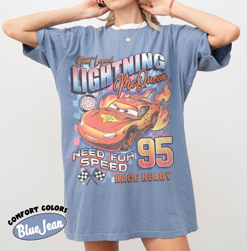 Puede incluir: Camiseta azul vaquero con un gr&aacute;fico de Rayo McQueen de la pel&iacute;cula Cars. El dise&ntilde;o incluye el texto "Street Legend Lightning McQueen", "Need for Speed" y "Race Ready". La camiseta tiene cuello blanco y mangas cortas.
