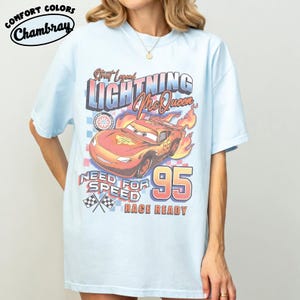 Puede incluir: Camiseta azul claro con un dise&ntilde;o de Rayo McQueen de la pel&iacute;cula Cars. El dise&ntilde;o incluye el texto "Street Legend Lightning McQueen", "Need for Speed" y "Race Ready", junto con el n&uacute;mero "95". La camiseta est&aacute; etiquetada como "Comfort Colors Chambray".