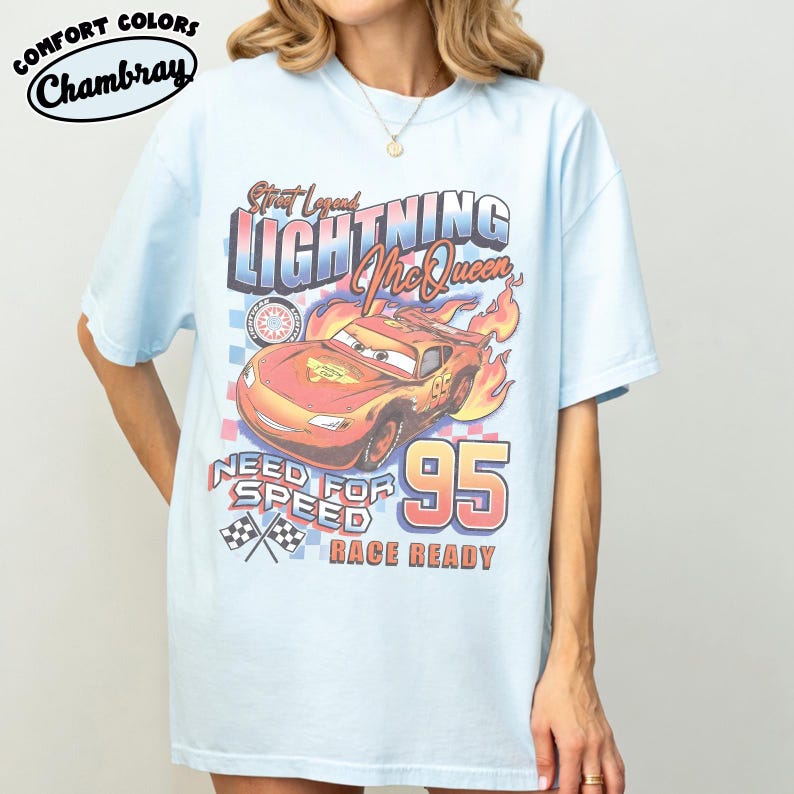 Puede incluir: Camiseta azul claro con un dise&ntilde;o de Rayo McQueen de la pel&iacute;cula Cars. El dise&ntilde;o incluye el texto "Street Legend Lightning McQueen", "Need for Speed" y "Race Ready", junto con el n&uacute;mero "95". La camiseta est&aacute; etiquetada como "Comfort Colors Chambray".