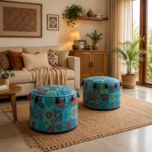Könnte beinhalten: Zwei runde Sitzhocker mit Patchwork-Design mit türkisfarbenen, blauen und grünen Blumenmustern. Jeder Hocker hat eine Reihe von türkisfarbenen Quasten mit rosa und schwarzen Akzenten. Sie stehen auf einem Jute-Teppich in einem Wohnzimmer.