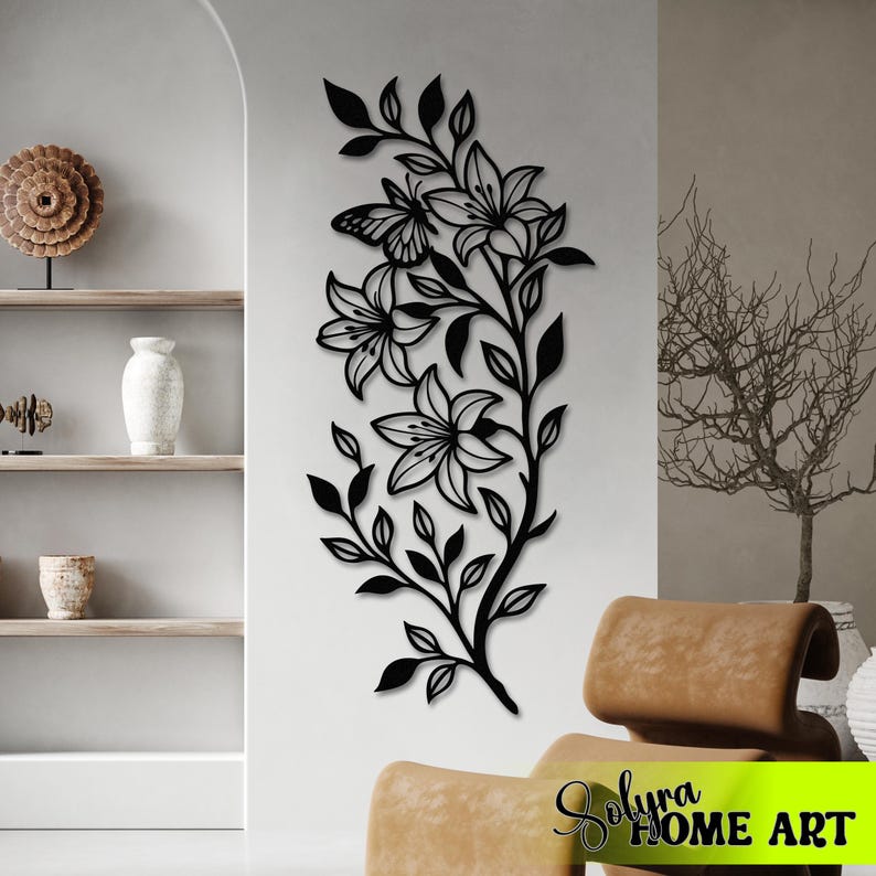 Puede incluir: Arte mural de metal negro con un dise&ntilde;o floral de lirios y una mariposa. La obra de arte est&aacute; montada en una pared blanca, ofreciendo una est&eacute;tica moderna. Un elemento decorativo para la decoraci&oacute;n del hogar.