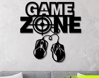 May include: Black wooden wall art featuring the words "GAME ZONE" and a target symbol. Two computer mouse silhouettes are connected to the text by a cable. The art is mounted on a light grey wall.