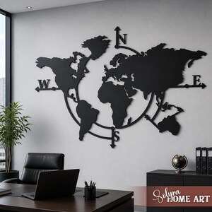 Peut inclure: Une décoration murale en métal noir représentant une carte du monde avec les points cardinaux (N, S, E, O) et un cadre circulaire. La carte est fixée sur un mur gris clair dans un cadre de bureau. L'image comprend également un bureau, une chaise et un petit globe.