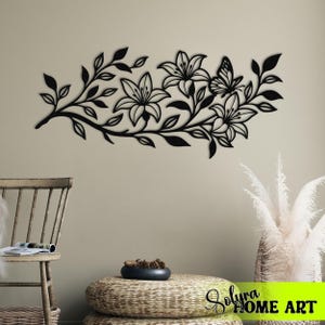 Puede incluir: Arte mural floral de metal negro con lirios y una mariposa. El dise&ntilde;o incluye hojas y tallos, creando una est&eacute;tica inspirada en la naturaleza. Adecuado para la decoraci&oacute;n interior del hogar.