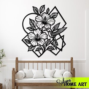 May include: Black metal wall art featuring a hummingbird, hibiscus flowers, and leaves. The design incorporates geometric shapes like circles and diamonds. The artwork is mounted on a white wall above a wooden bench with white cushions.
