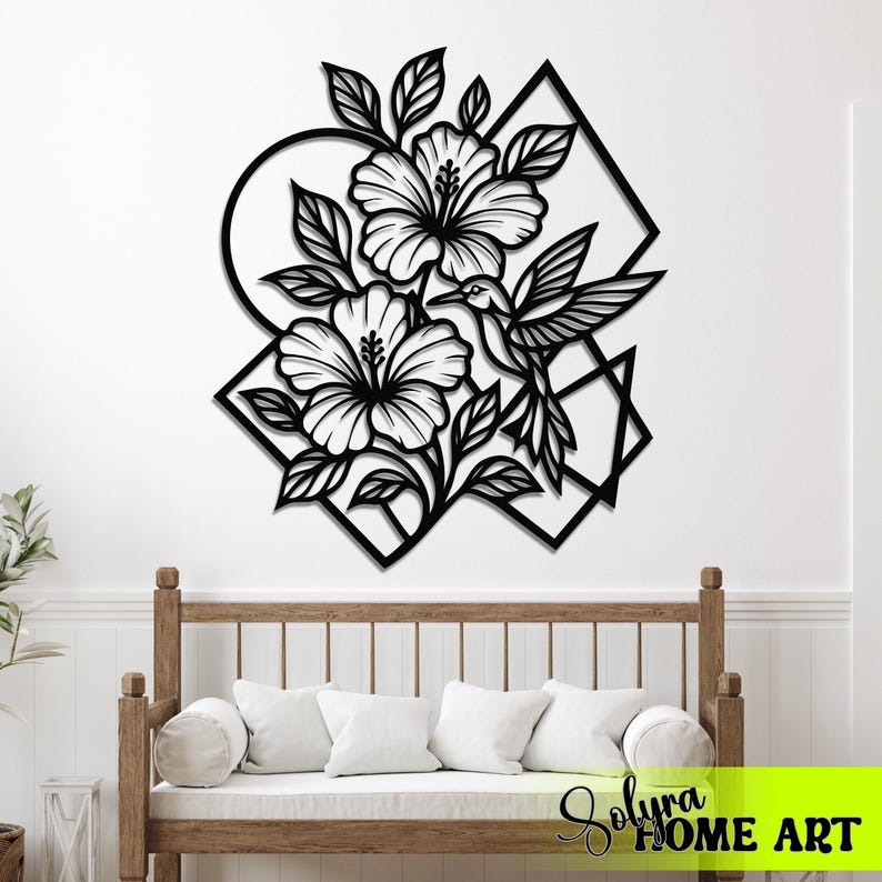 May include: Black metal wall art featuring a hummingbird, hibiscus flowers, and leaves. The design incorporates geometric shapes like circles and diamonds. The artwork is mounted on a white wall above a wooden bench with white cushions.