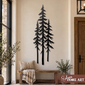 May include: A tall, black metal wall art piece featuring a silhouette of three pine trees. The design displays detailed branches and trunks, mounted vertically on a plain wall. The artwork is positioned above a wooden bench with a throw blanket.