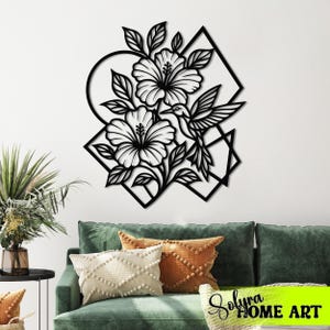 May include: Black metal wall art featuring a floral design with hibiscus flowers and a hummingbird. The artwork is set against geometric shapes, including a circle and a diamond. This decorative piece is ideal for home decor.