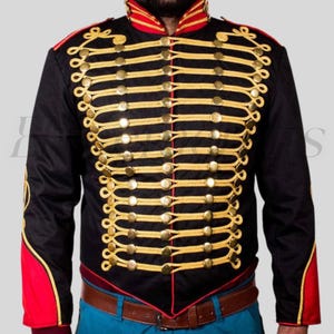 May include: Black military-style jacket with gold-colored trim and buttons. The jacket features red accents on the collar and cuffs. The design includes multiple rows of gold-colored rope-like trim across the chest and sleeves. A brown belt is visible at the waist.