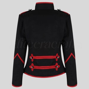 May include: Black jacket with red trim and accents. The jacket features a high collar, decorative silver buttons, and red piping along the edges and sleeves. The back view showcases the tailored design and military-inspired style.