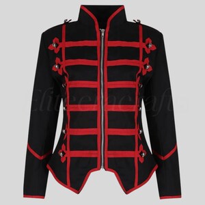 May include: Black jacket with red accents. The jacket features a high collar, a front zipper, and decorative red bands across the chest and sleeves. Small silver buttons and red bows add detail. The jacket has a fitted silhouette.