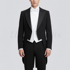 Op de afbeelding: Een formele zwarte smoking met een wit overhemd, vest en vlinderdas. De smoking heeft een dubbelbreasted jasje met satijnen revers en een staartjas-ontwerp. De outfit wordt gecompleteerd met een zwarte broek.