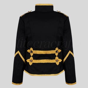 May include: Black jacket with gold trim and accents. The jacket features a high collar, gold braid detailing on the sleeves and back, and decorative gold buttons. The jacket's design is reminiscent of military or formal wear.