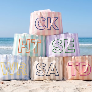 Può includere: Una pila di sei borse tote rettangolari in tela con strisce verticali in colori pastello. Ogni borsa presenta due grandi lettere maiuscole in un colore a contrasto stampate sul davanti: CK, HT, SE, WR, SA e TD.