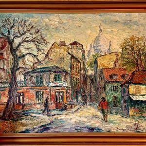 May include: Oil painting of a European street scene with buildings, trees, and figures. The artwork features a palette of warm colors, including reds, oranges, and greens, with a prominent church in the background. The painting is framed in a wooden frame.