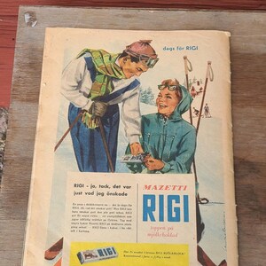 Puede incluir: Un anuncio vintage de chocolate RIGI con una ilustraci&oacute;n de dos esquiadores con ropa de invierno. El texto incluye 'dags f&ouml;r RIGI', 'MAZETTI RIGI' y 'toppen p&aring; mj&ouml;lkchoklad' junto a un p&aacute;rrafo promocional y una imagen de una tableta.