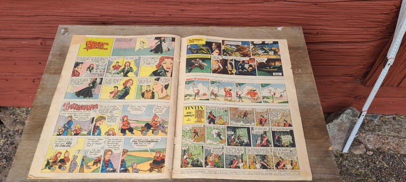 Puede incluir: Una revista de c&oacute;mic vintage abierta que presenta m&uacute;ltiples paneles y tiras ilustradas a color. Las p&aacute;ginas contienen varios personajes y globos de di&aacute;logo en diferentes idiomas, con el t&iacute;tulo Tintin claramente visible en una de las secciones.