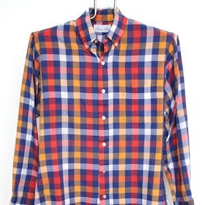 Op de afbeelding: Een button-down overhemd met lange mouwen en een kleurrijk ruitpatroon in rood, blauw, oranje, geel en wit. Het overhemd hangt aan een hanger tegen een witte achtergrond. De merknaam "Robert Alan" is zichtbaar.