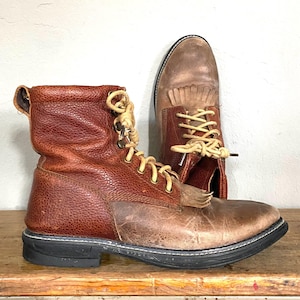 May include: A pair of brown leather boots with laces and fringe details. The boots have a rugged look and are made of a durable material.
