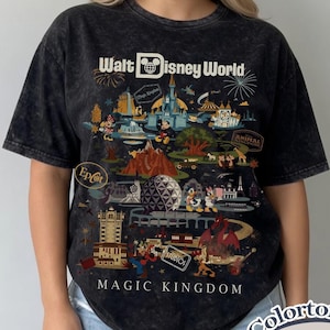 Puede incluir: Camiseta negra con lavado mineral que presenta un gr&aacute;fico colorido de las atracciones de Walt Disney World, incluyendo el castillo de Cenicienta y Mickey Mouse. El texto "Walt Disney World" y "Magic Kingdom" se muestra en la camiseta.
