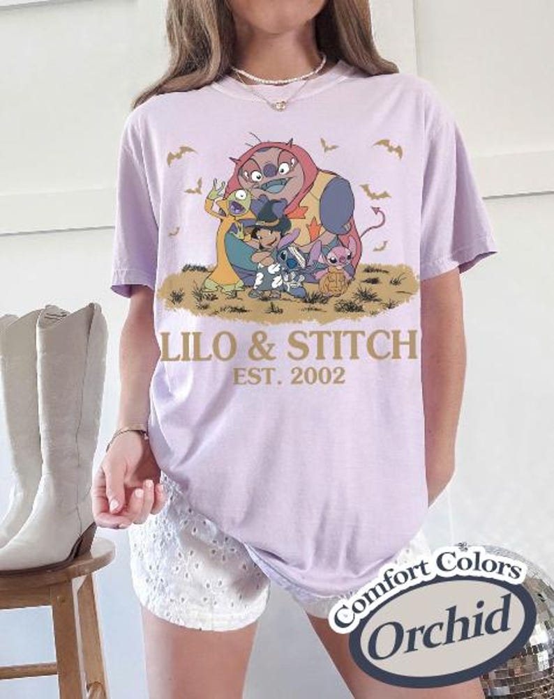 K&ouml;nnte beinhalten: Ein helllila T-Shirt mit einer Grafik von Lilo & Stitch-Charakteren und dem Text "Lilo & Stitch EST. 2002". Das Design umfasst Stitch, Lilo und andere Charaktere. Das Shirt ist ein Comfort Colors Orchid.