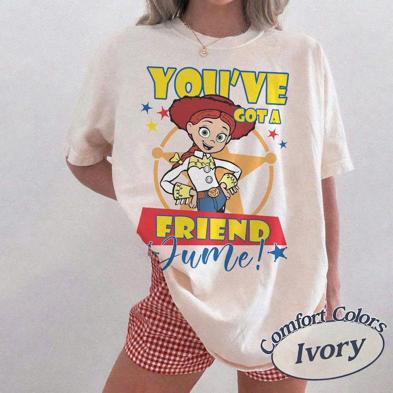 Op de afbeelding: Ivoor kleurig T-shirt met een afbeelding van Jessie uit Toy Story en de tekst "You've Got a Friend in Me!". Het ontwerp bevat een sheriff-badge en sterren. Het shirt is van het merk Comfort Colors.