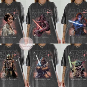 May include: Six dark gray t-shirts featuring Star Wars characters and the Star Wars logo. Each shirt has a different character: Princess Leia, Darth Vader, Anakin Skywalker, Boba Fett, Chewbacca, and Grogu. The text "ATTACK OF THE CLONES" is below each character.