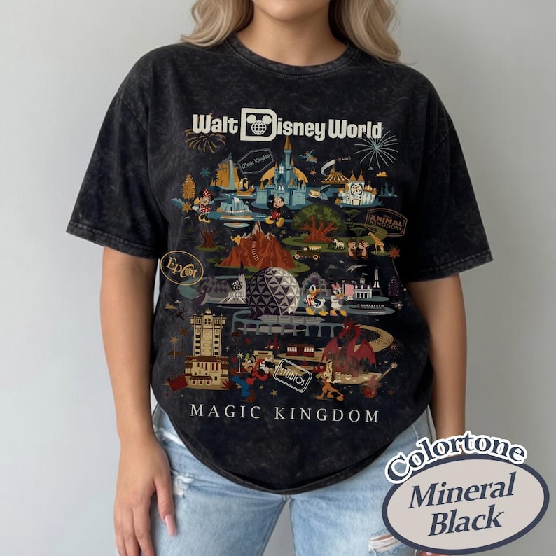 Puede incluir: Camiseta negra con lavado mineral que presenta un gr&aacute;fico colorido de las atracciones de Walt Disney World, incluyendo el castillo de Cenicienta y Mickey Mouse. El texto "Walt Disney World" y "Magic Kingdom" se muestra en la camiseta.