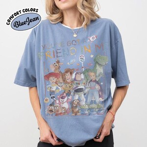 Pu&ograve; includere: Una t-shirt blu a maniche corte con una stampa grafica di vari personaggi animati del franchise Toy Story. Il testo "YOU'VE GOT A FRIEND IN ME" &egrave; stampato sopra i personaggi. La t-shirt presenta un girocollo e una vestibilit&agrave; ampia.