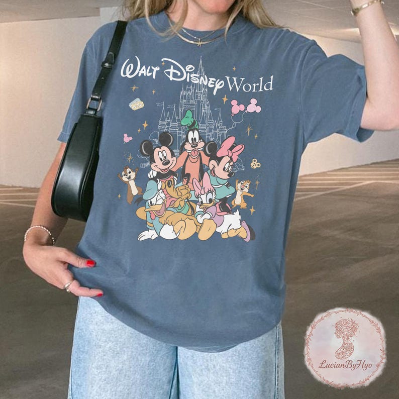 May include: Blue t-shirt featuring the text "Walt Disney World" above a graphic of Mickey Mouse, Minnie Mouse, Goofy, Donald Duck, Daisy Duck, and other Disney characters. The design includes a castle and stars.
