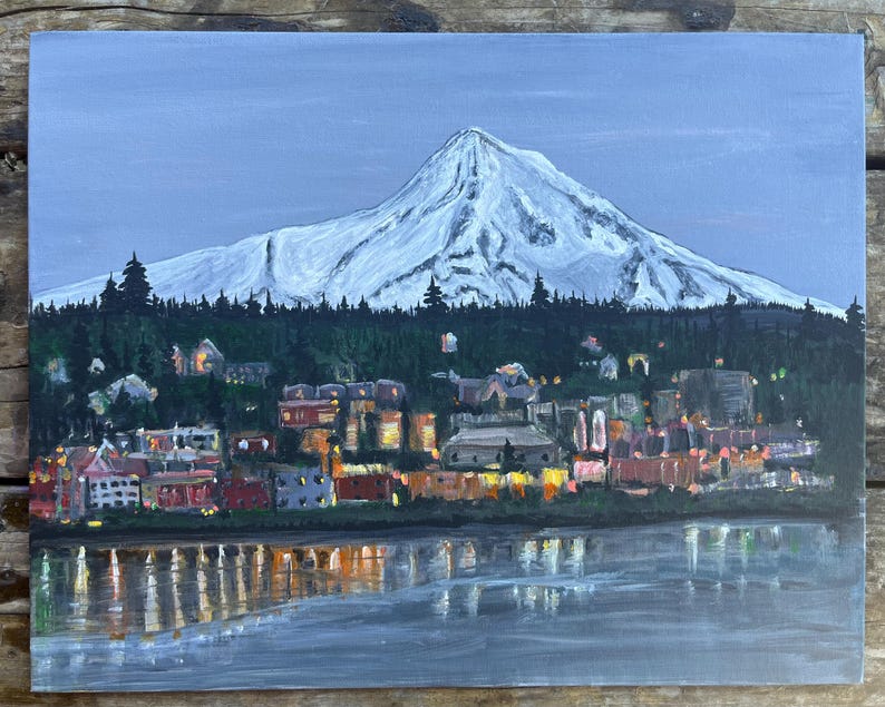 May include: A painting of a snow-capped mountain with a town at the base. The town is lit up with lights, and the mountain is reflected in the water in the foreground.