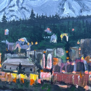 May include: A painting of a mountain range with a town in the foreground. The mountain is painted in shades of blue and white, while the town is painted in shades of brown, orange, and yellow. The town is lit up with lights, suggesting it is nighttime.