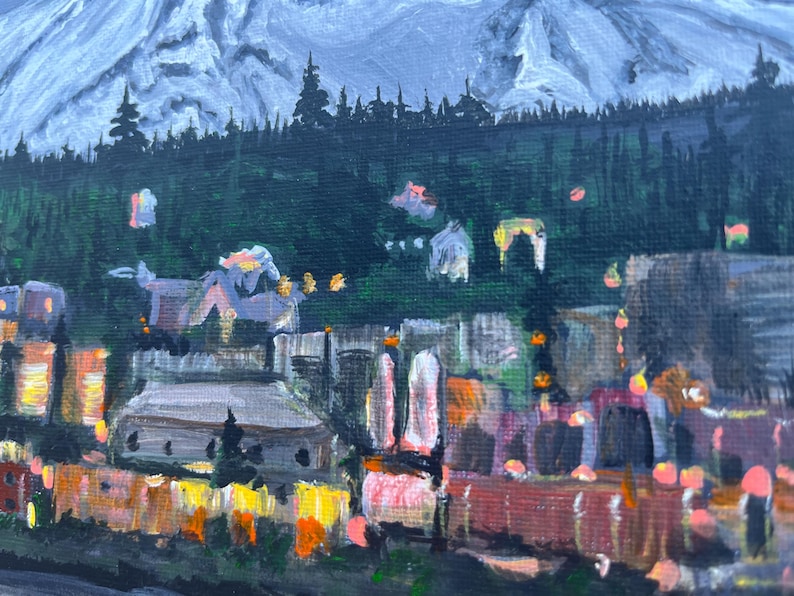 May include: A painting of a mountain range with a town in the foreground. The mountain is painted in shades of blue and white, while the town is painted in shades of brown, orange, and yellow. The town is lit up with lights, suggesting it is nighttime.