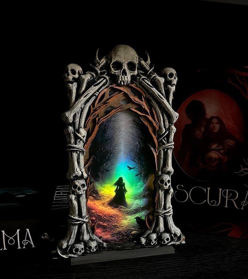 May include: A gothic-style decorative frame featuring a central image of a silhouetted figure in a colorful, ethereal landscape. The frame is adorned with skulls and bone-like structures, creating a dark fantasy aesthetic.