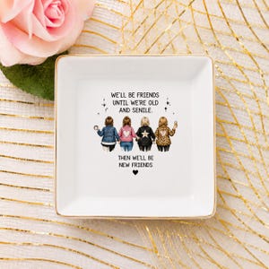 Puede incluir: Un plato cuadrado de cer&aacute;mica blanca con un gr&aacute;fico de cuatro amigos de pie uno al lado del otro. El texto dice: WE'LL BE FRIENDS UNTIL WE'RE OLD AND SENILE. THEN WE'LL BE NEW FRIENDS. El plato tiene un borde dorado y un acabado brillante.