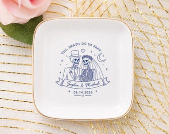 Può includere: Un piattino quadrato in ceramica bianca con bordo dorato. Al centro è presente un'illustrazione a linee blu di due scheletri, uno con cilindro e l'altro con velo, con il testo "TILL DEATH DO US PART", "Sophia & Michael" e "09.14.2026".