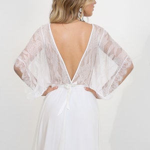 May include: White lace wedding dress with a deep V-back and a flowing skirt.