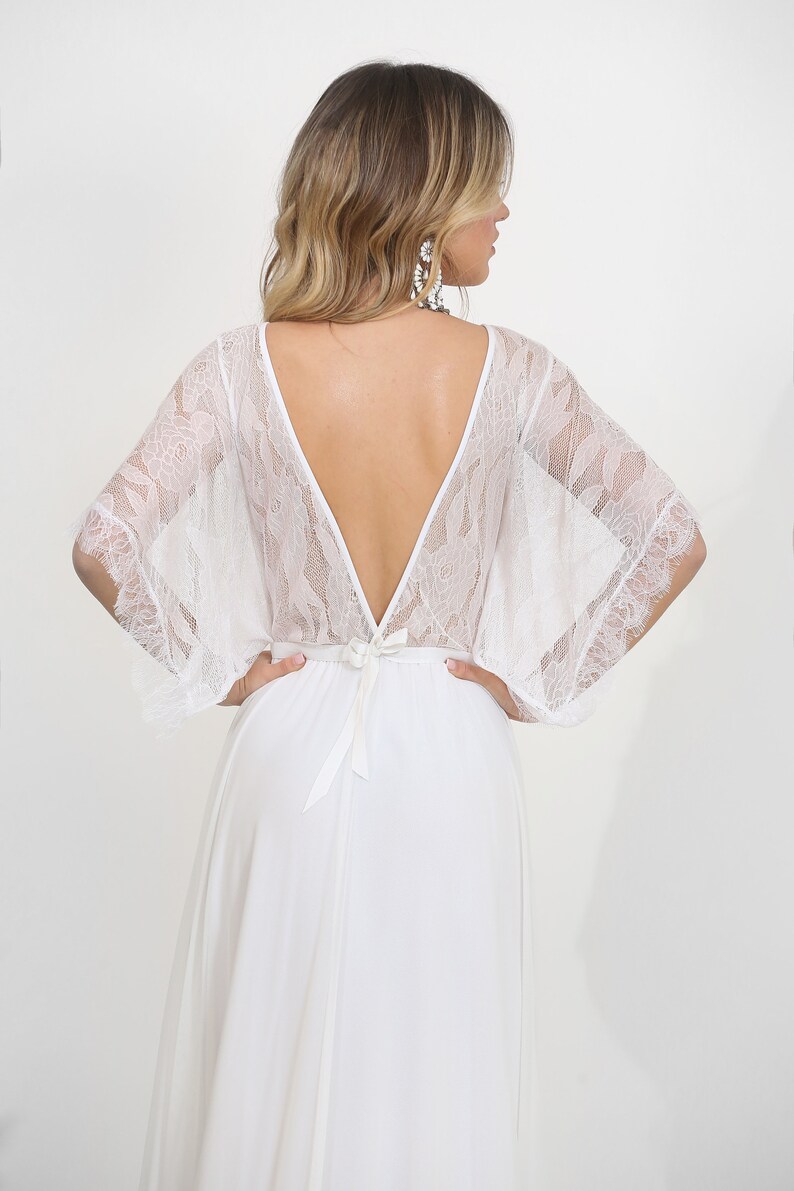 May include: White lace wedding dress with a deep V-back and a flowing skirt.