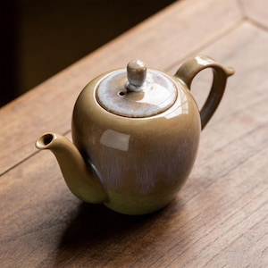 May include: A set of three ceramic mugs with a speckled, matte finish. The mugs are in shades of cream, light gray, and dark gray. Each mug has a simple, minimalist design, perfect for coffee or tea.