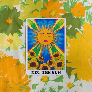The Sun card from the Rainbow Heart Tarot against  yellow, orange and green retro floral fabric background