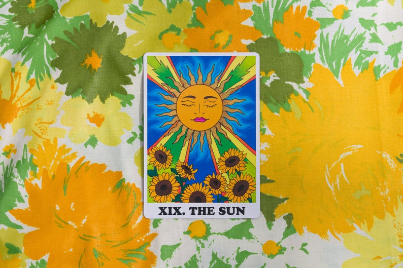 The Sun card from the Rainbow Heart Tarot against  yellow, orange and green retro floral fabric background