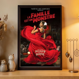 Könnte beinhalten: Gerahmtes Poster mit einer Frau in einem roten Kleid. Der Text "LA FAMILLE EST UN MONSTRE" und "INTERVIEW WITH THE VAMPIRE" ist zu sehen. Der Hintergrund ist dunkel mit Figuren im Schatten.