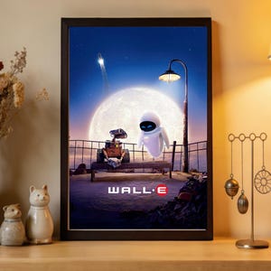 May include: Framed print featuring WALL-E and EVE from the animated film. The artwork depicts the robots on a bench under a full moon, with a rocket launch in the background. The title "WALL-E" is displayed at the bottom.